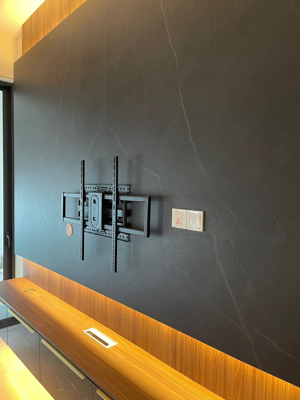 Detail of the walnut floating shelf, stone panel and cable management