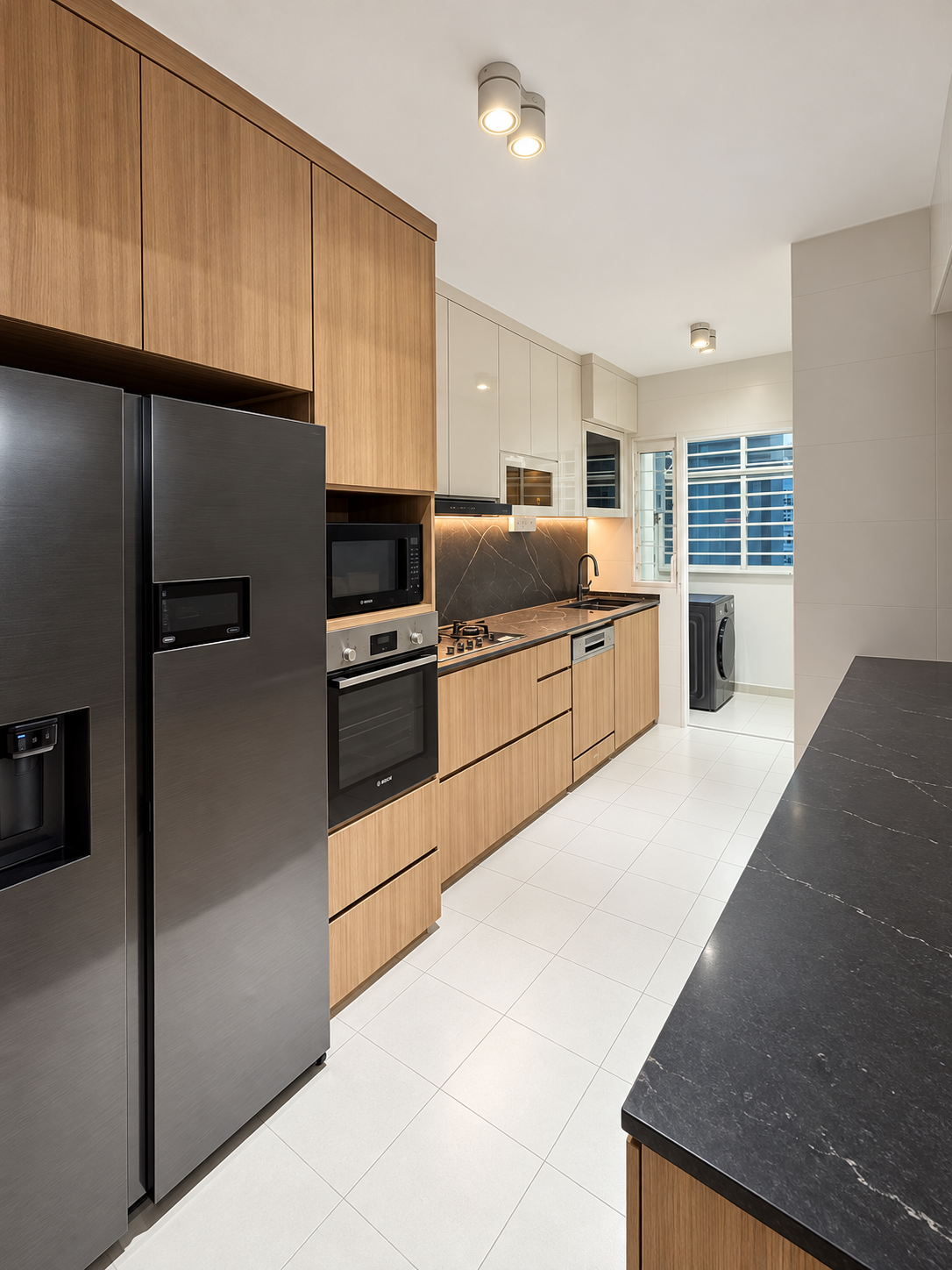 Kitchen with warm oak lower cabinets, stone marble worktop and tall larder column