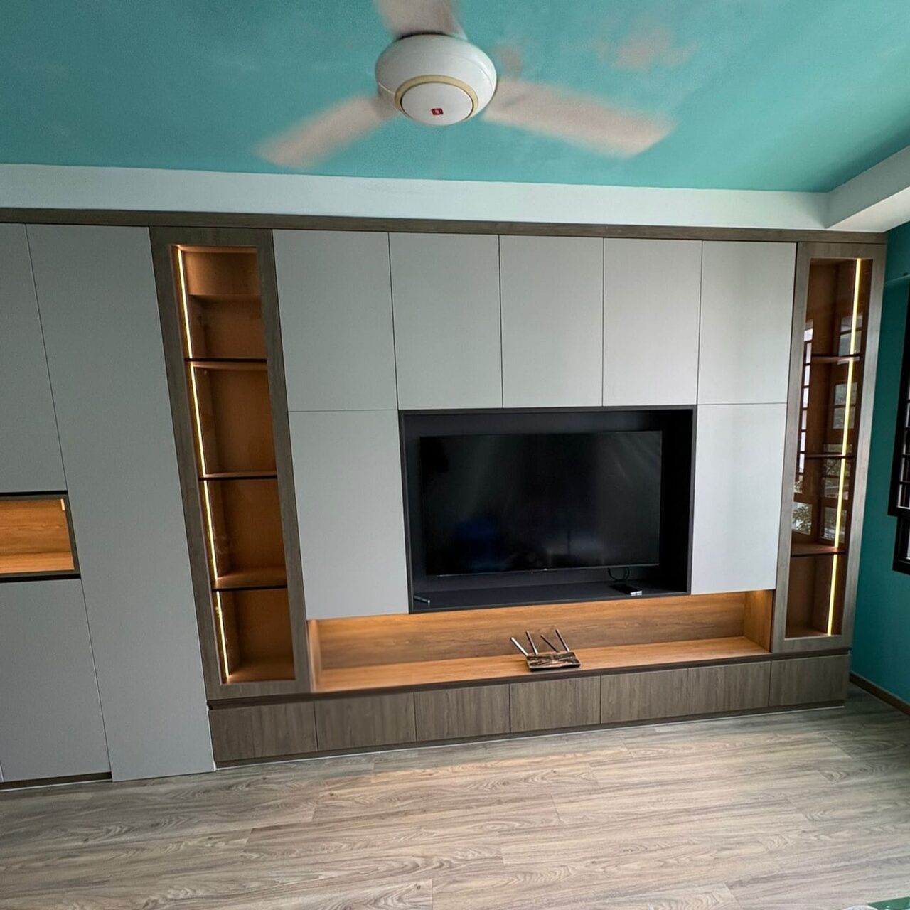 Recessed TV between lit glass display niches over a floating oak console
