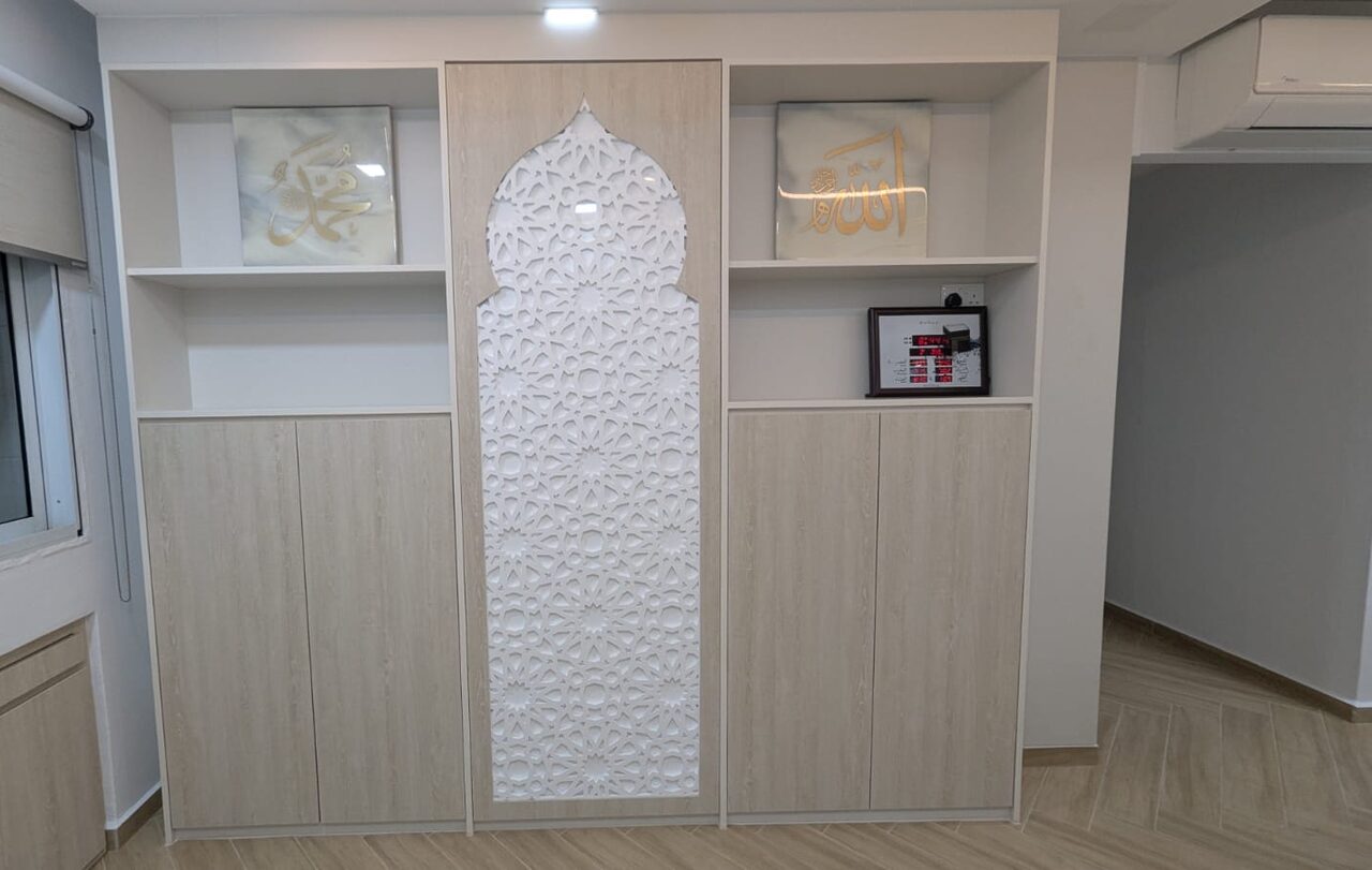 Light-oak prayer feature wall with a central laser-cut mihrab arch and flanking calligraphy niches