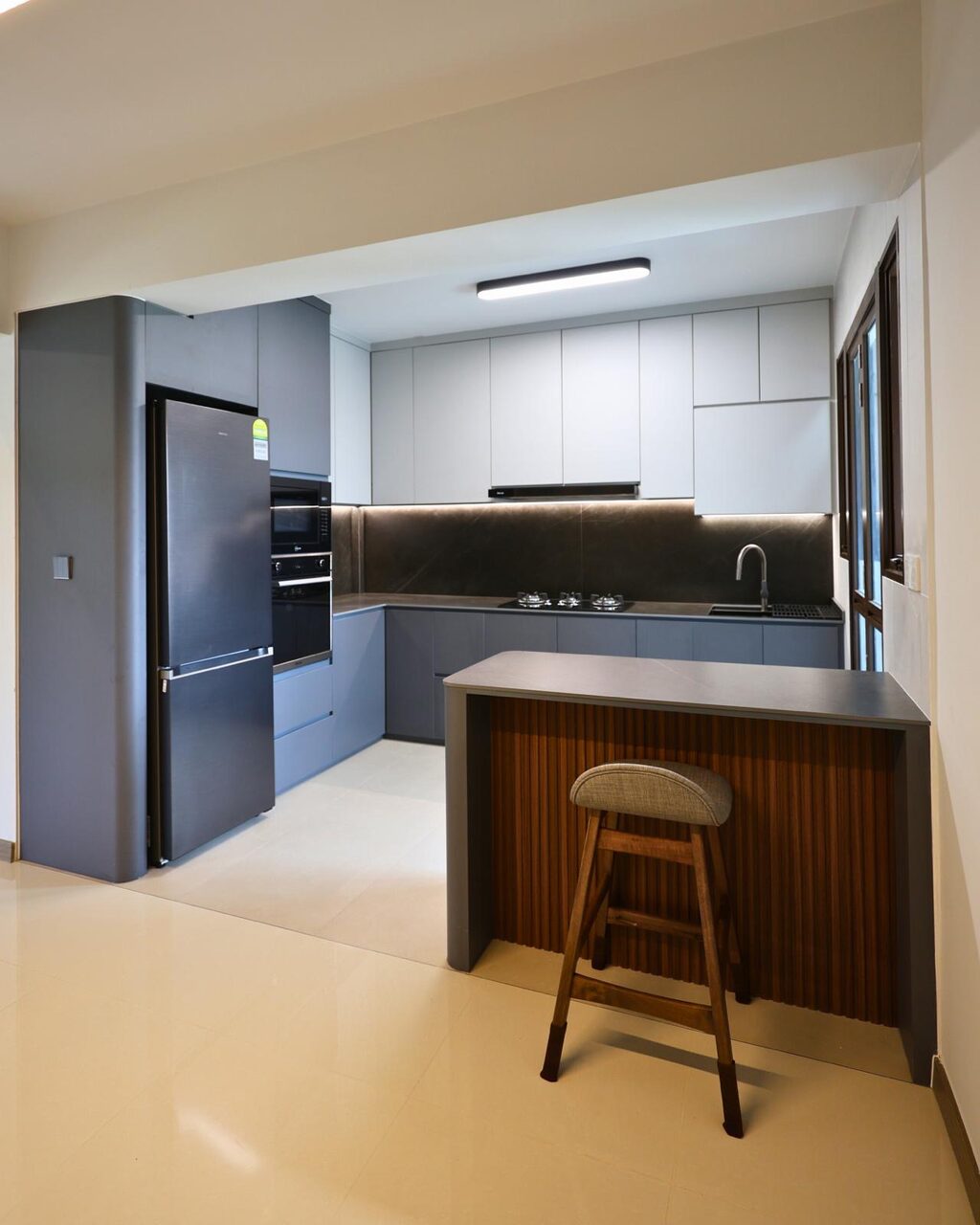 Wider kitchen view with the fluted-walnut peninsula breakfast bar and appliance tower