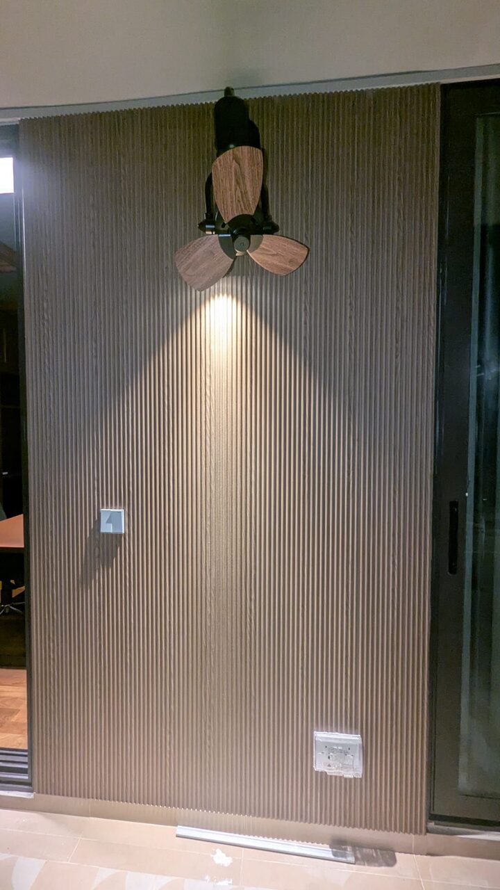 Indoor full-height fluted feature wall washed by a downlight