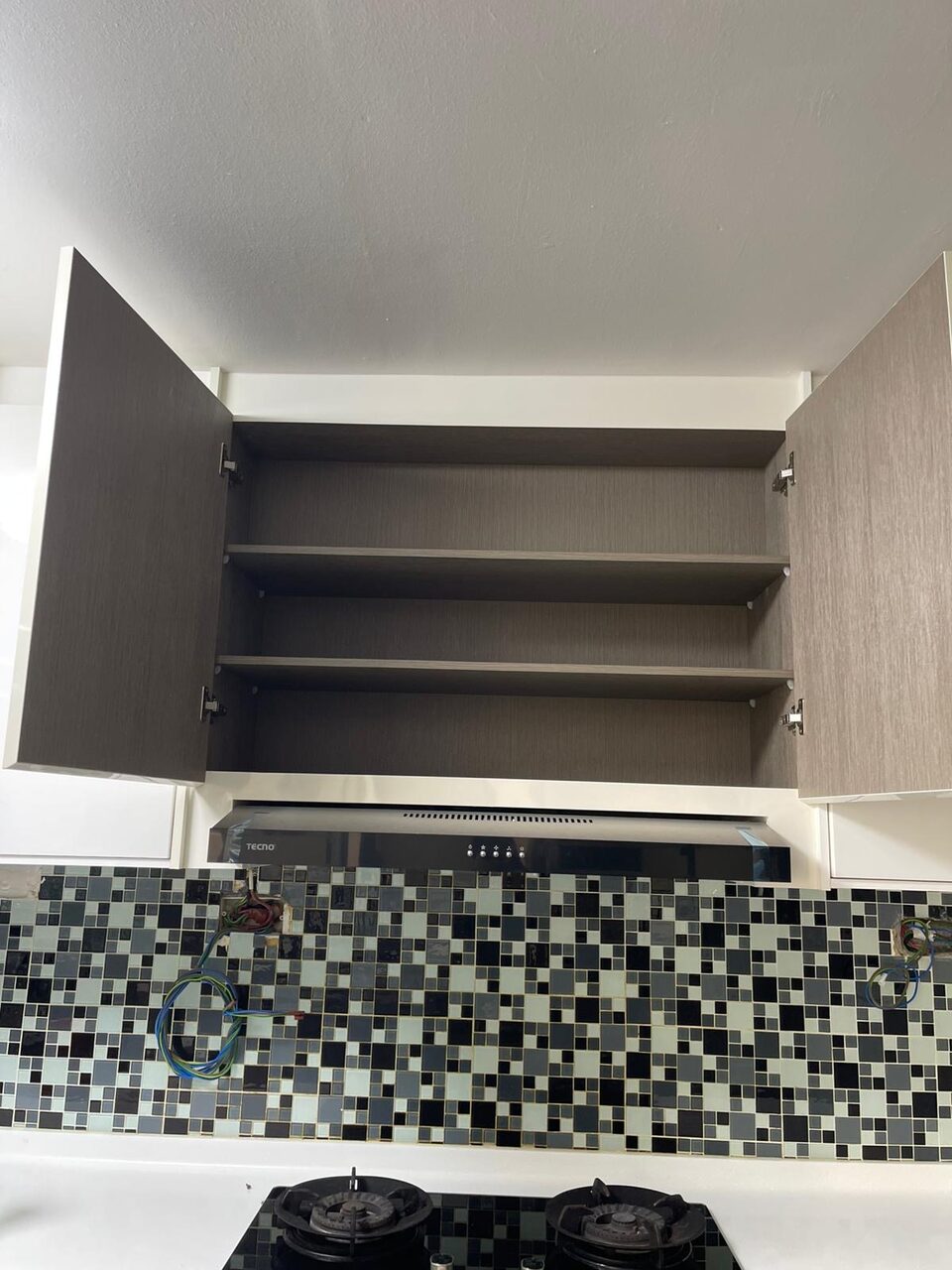 Kitchen overhead cabinet open, hood and mosaic