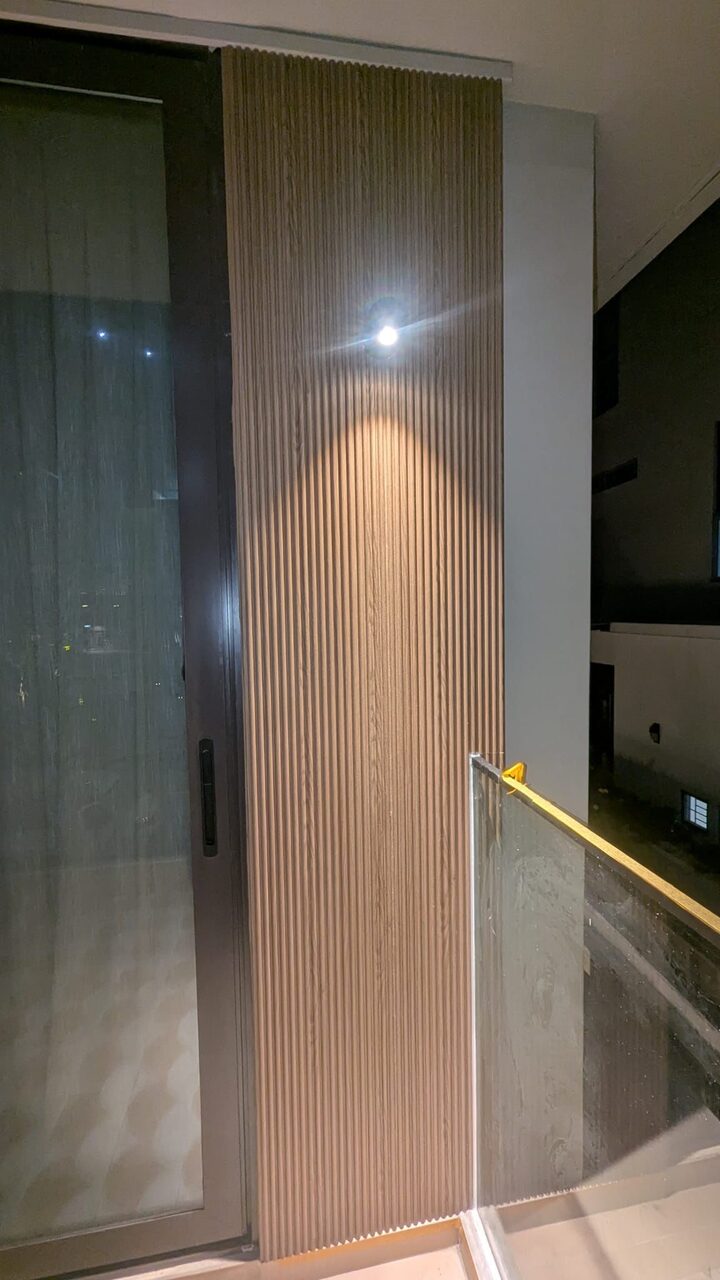 Fluted cladding column lit at night beside the glass slider