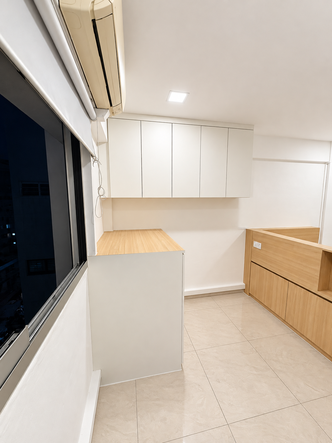 Window-angle view of the white study unit and overhead cabinets with night cityscape