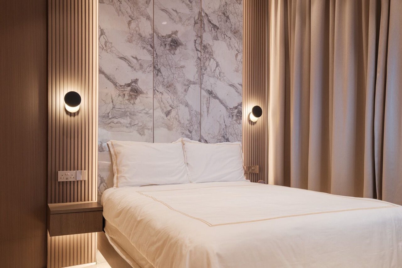 Marble headboard bedroom with fluted-oak panels and orb sconces