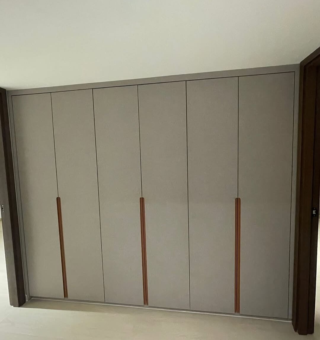 Linen-grey six-door wardrobe with vertical copper handles