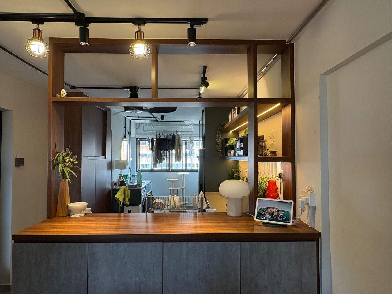 Walnut grid room divider with concrete-grey storage base, seen from the living room